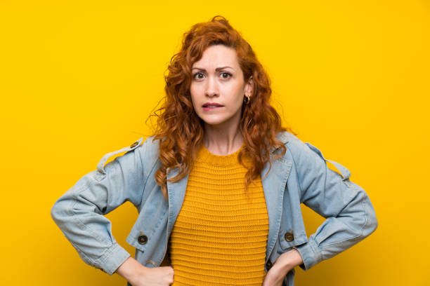 istock Redhead woman over isolated yellow background having doubts and with confuse face expression 1189550692