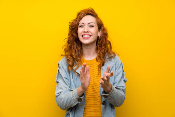 istock Redhead woman over isolated yellow background applauding 1189551683