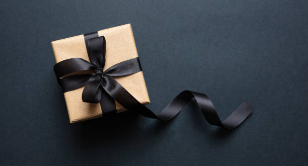 istock Gift box with black ribbon against black background, Black Friday concept. 1189551701