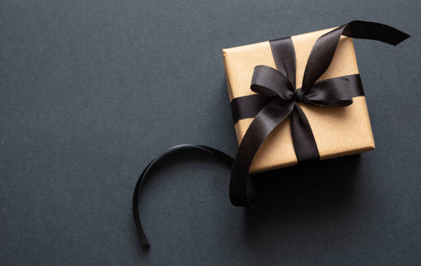 istock Gift box with black ribbon against black background, Black Friday concept. 1189551705