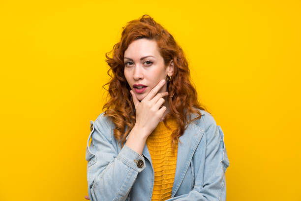 istock Redhead woman over isolated yellow background standing and thinking an idea 1189552652