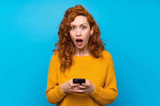 istock Redhead woman with yellow sweater surprised and sending a message 1189553869