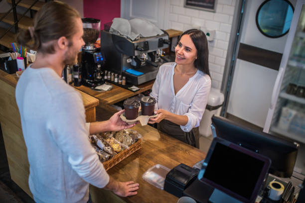 istock Smiling beautiful barista giving takeaway coffee to customer 1189554872
