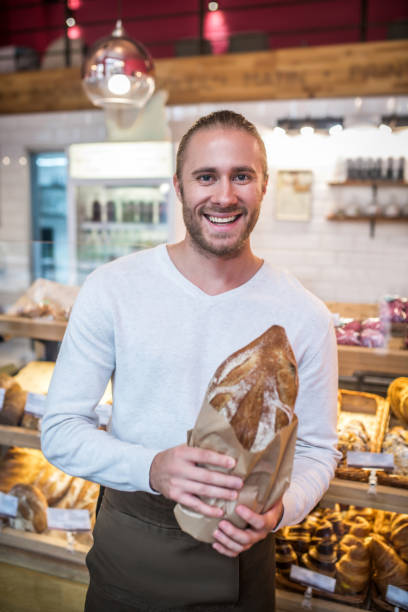 istock Smiling bearded man holding just baked bread standing in bakery 1189555075