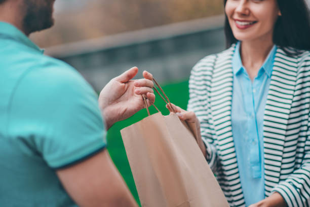 istock Woman smiling while talking to delivery man and taking her bag 1189555105
