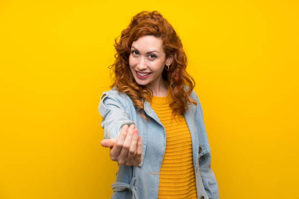 istock Redhead woman over isolated yellow background inviting to come 1189555334