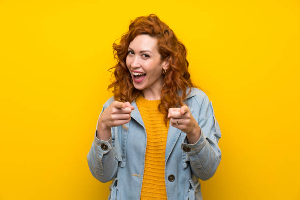 istock Redhead woman over isolated yellow background points finger at you 1189556496