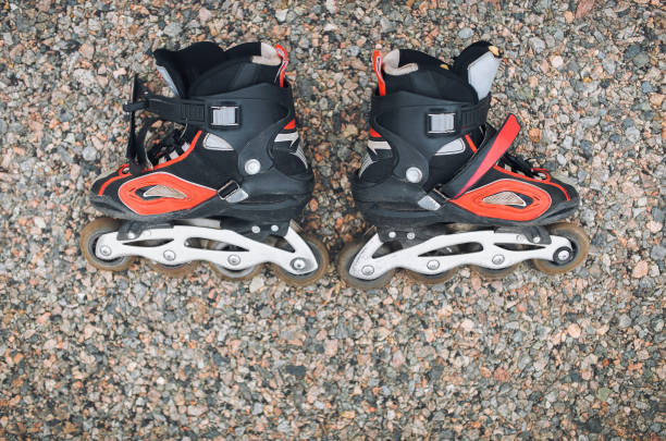 istock Black roller skates with red stripes lie on the pavement. Top view, copy space, stone background. 1189557609