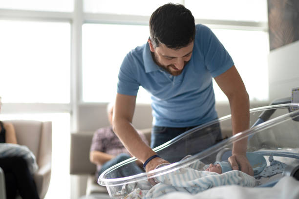 vater schaut sein neugeborenes im krankenhaus an - hispanic male stock-fotos und bilder