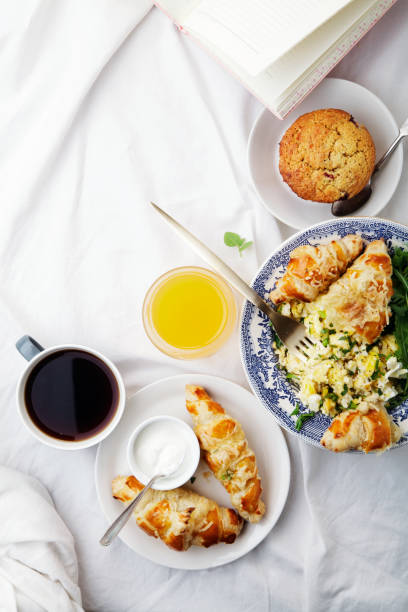 istock Breakfast in bed. Scrambled eggs with cheese croissants, raspberry muffin and black coffee. Morning treat concept. Vertical composition with copy space. 1189561301