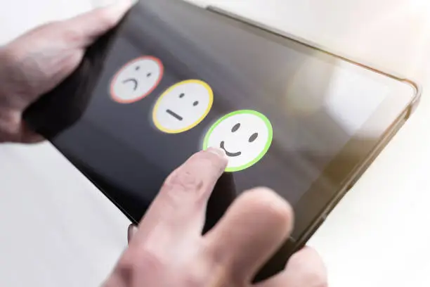 pleased person giving positive feedback by touching smiley face on digital tablet touchscreen, service quality rating concept
