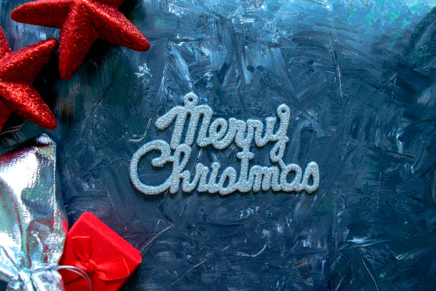 istock Merry Christmas phrase and gift boxes with red stars on grey 1189564113