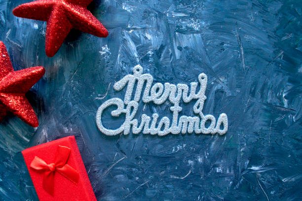 istock Merry Christmas phrase and gift boxes with red stars on grey back 1189564114