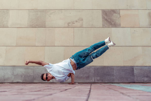 young active dancer, stand on his hand, flies in air like superman, sport man, summer city, break-dancer pose, hip-hop movement, modern dance style, youth lifestyle. Street urban fitness motivation joven bailarín activo, de pie en su mano, vuela en el aire como superman, hombre deportivo, ciudad de verano, pose break-dancer, movimiento hip-hop, estilo de baile moderno, estilo de vida juvenil. motivación de fitness urbano en la calle.