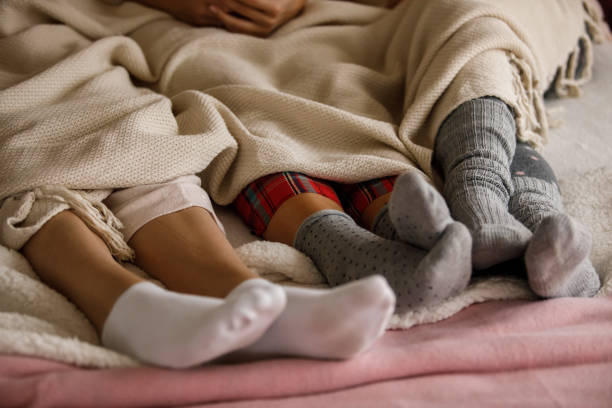 Lower section of three young girlfriends having a slumber party Lower section of three unrecognizable young women lying in bed together and relaxing in their cozy pajamas and sock while enjoying their slumber party. slumber party stock pictures, royalty-free photos & images