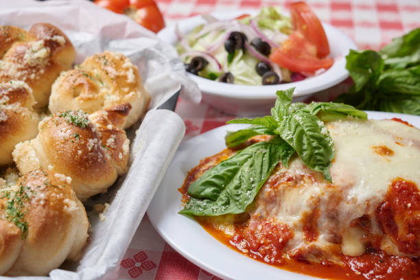 Italian food combination of lasagna, small side salad and garlic knots with whole raw vegetables  on the background stock photo