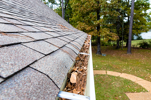 Leave and pinestraw filling gutters on home
