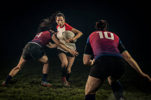 Women playing rugby on field Female rugby player pushing her opponent and running away with ball. rugby team stock pictures, royalty-free photos & images