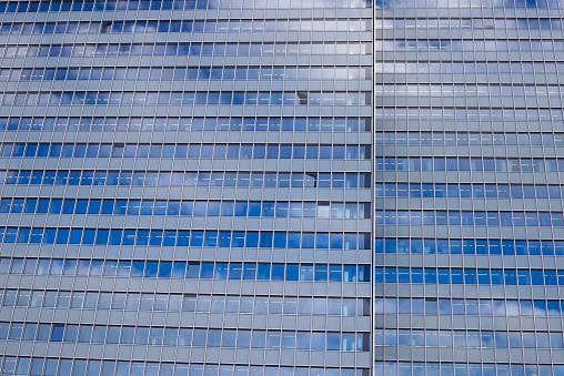 View on isolated glass facade of skyscraper with countless windows and reflection of clouds and sky - Düsseldorf, Germany