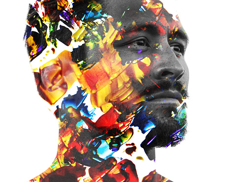 Paintography. Double exposure portrait of a man with strong features combined with handmade painting of colorful brushstrokes which dissolve into his skin