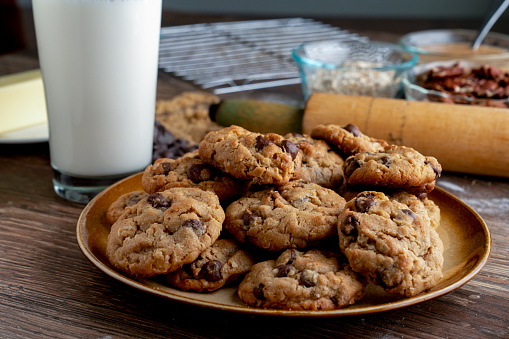 A frosty cold glass of milk, with a plate of peanut butter, oatmeal, dark and semi-sweet chocolate chip cookies
