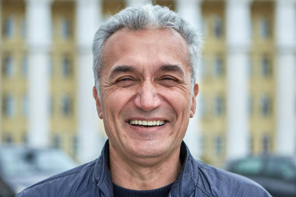 The joyful face of a middle-aged man over 50 years Closeup laughing face of an elderly businessman, civil servant, doctor or television presenter. Portrait of a joyful caucasian man over fifty years, with short gray hair outdoors, near public building minsk photos stock pictures, royalty-free photos & images