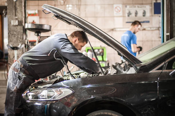istock Car mechanic repairer service technician checks and repairs auto engine 1189586836