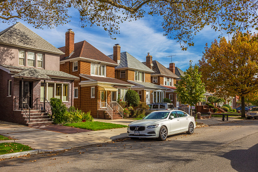 Houses along the street in Bay Ridge, Brooklyn, New York, USA. Street, sidewalk, trees in autumn colors and Luxury Volvo Sedan parked along the road  are in the image. Canon EOS 6D (full frame sensor) DSLR and Canon EF 24-105mm f/4L IS lens.