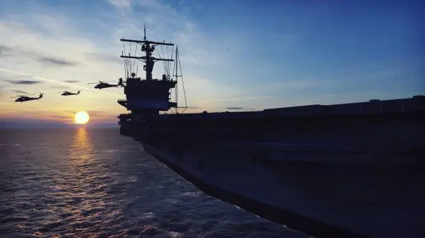 Military helicopters Blackhawk take off from an aircraft carrier at sunrise in the endless sea.