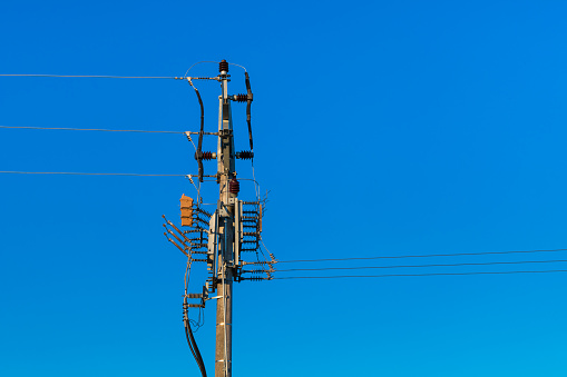 Power line pole with cables and isolator switches for disconnect of electric circuit current. Disconnector on transmission tower. For safe service, maintenance or repair. Industrial infrastructure