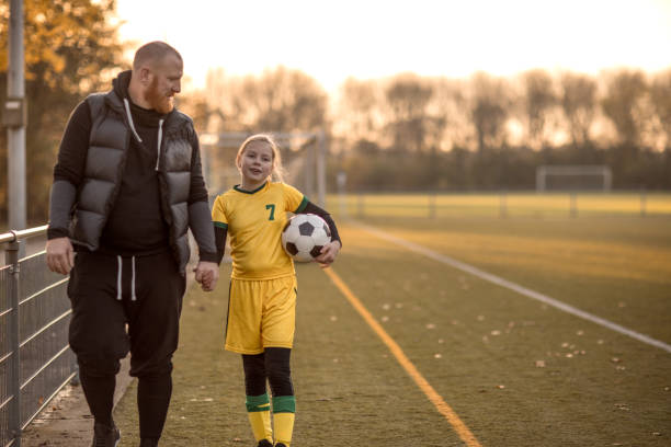 Soccer father sports chaperone Soccer Father accompanying his daughter to football training on a summer autumn day father and daughter stock pictures, royalty-free photos & images