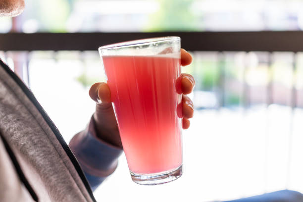 mann sitzt draußen halten trinkglas von rot rosa limonade cocktailsaft nahaufnahme der getränk farbe - strawberry fruit single object food stock-fotos und bilder