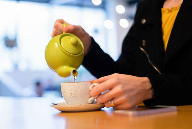 istock Woman Pouring Tea from Teapot into Tea Cup 1189601410