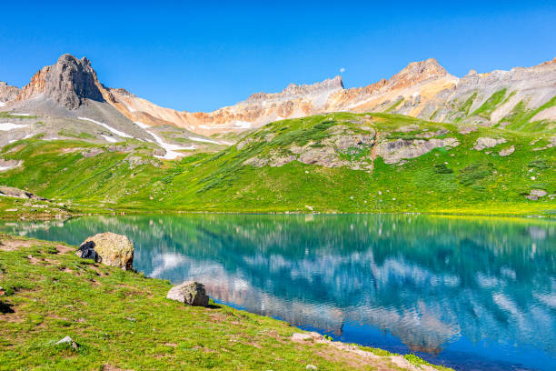 Landscape open view of green grass meadow field and Ice lake water reflection near Silverton, Colorado in August 2019 summer on summit Landscape open view of green grass meadow field and Ice lake water reflection near Silverton, Colorado in August 2019 summer on summit ice lakes colorado stock pictures, royalty-free photos & images