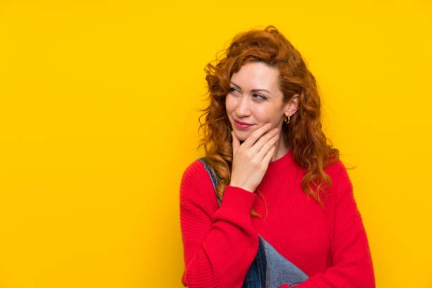 istock Redhead woman with overalls over isolated yellow wall thinking an idea 1189602267