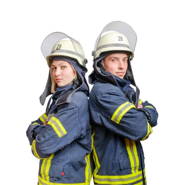 Photo of Young couple of firefighters with folded arms standing back-to-back wearing uniform and helmets