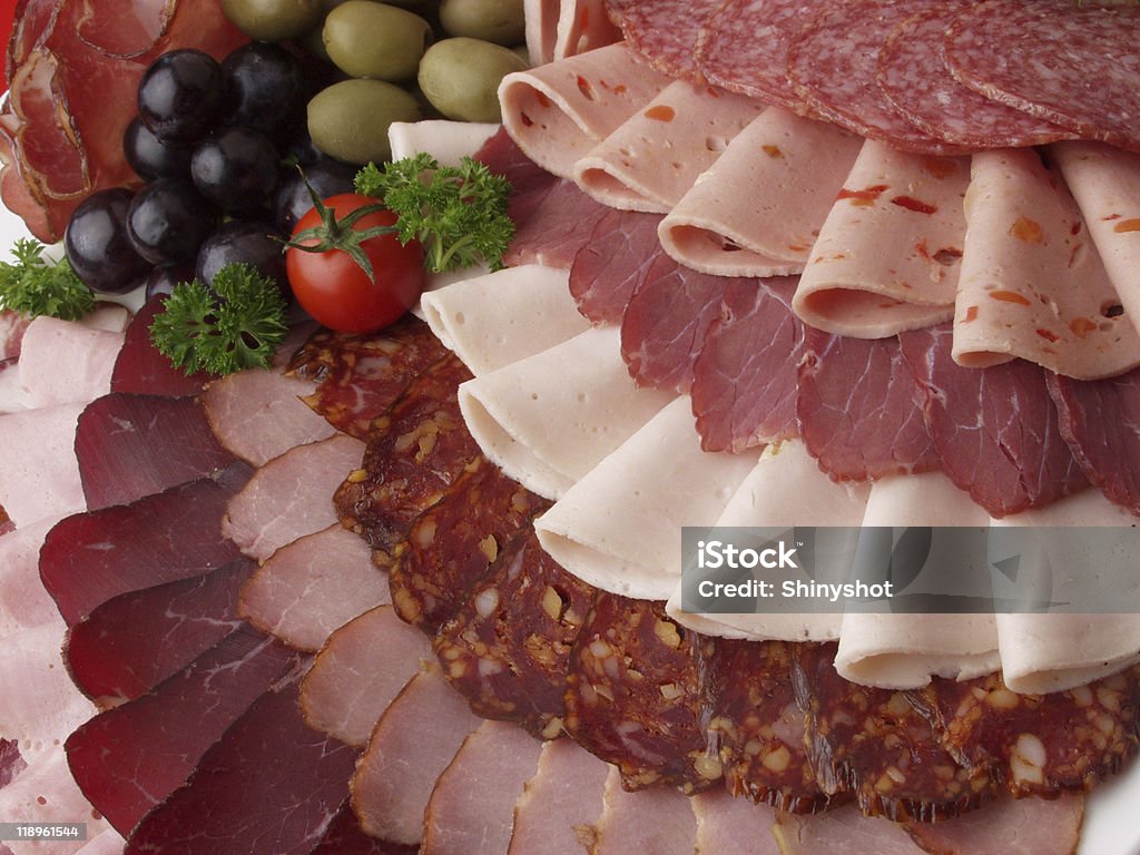 Plate with beautifully arranged deli meat detail of meat delicatessen plate arranged with cherry tomato, olives and parsley Arrangement Stock Photo