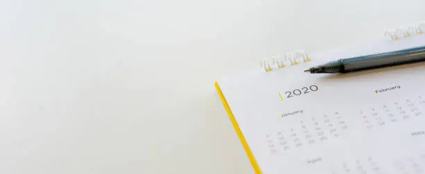 Photo of close up side view on  white calendar schedule background with pen to make appointment meeting or manage timetable each day for planning work in new year 2020 resolution concept