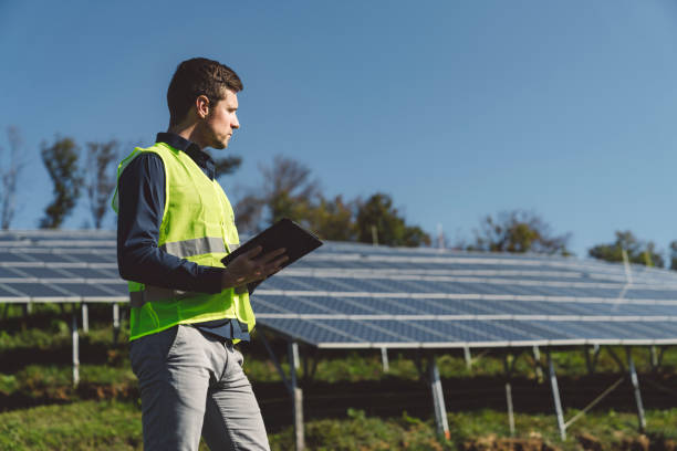 istock Man in reflective vest holding a tablet working with solar panels 1189616936