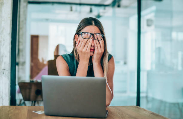 机に座って頭痛を伴う女性起業家 - distraught ストックフォトと画像