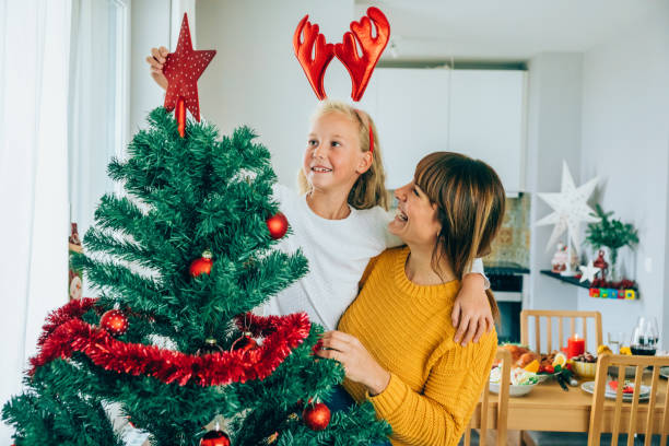 istock Mother and daughter putting star on the Christmas tree 1189618235