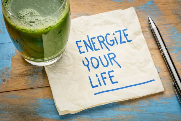 energize your life - inspirational handwriting on a napkin with a glass of green juice, healthy eating and lifestyle concept