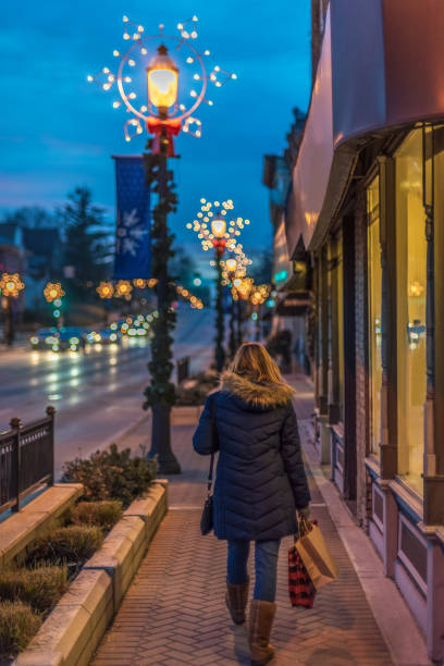 크리스마스 시즌 동안 쇼핑백으로 시내를 걷는 여성의 뒷모습 - retail night shopping christmas 뉴스 사진 이미지