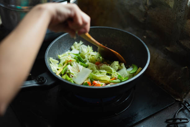 istock women cooking fried vegetables in the kitchen 1189656745