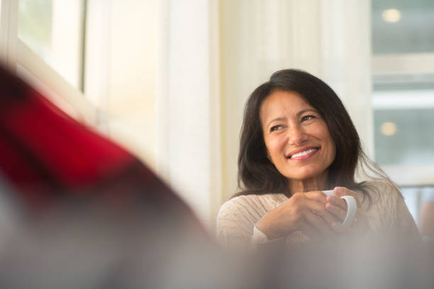 istock Hispanic woman sitting on the sofa drinking coffee. 1189666927