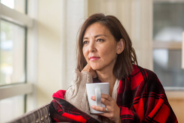 istock Mature woman looking out the window feeling sad. 1189667521