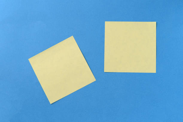 istock Two yellow sticker notes on a blue background with copy space. Business concept, horizontal mock-up 1189682430