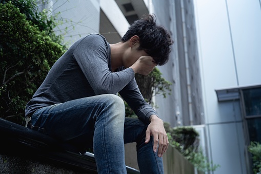 Un hombre asiático sentado al aire libre con decepción. photo
