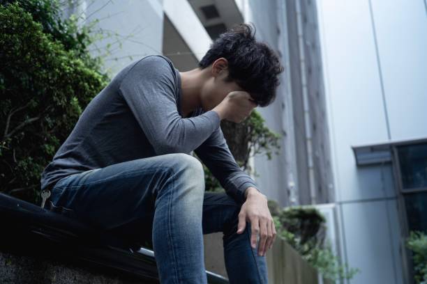 An asian man sitting outdoor with disappointment. sitting alone with stuck on something. hopelessness stock pictures, royalty-free photos & images