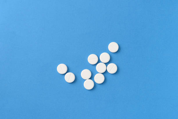 istock White round pills scattered on a blue background, top view. Medical pharmacy concept 1189683316